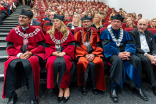 Representatives of the academic community wearing ceremonial academic gowns attend an event in the auditorium.