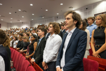 Participants stand between rows of red seats in the auditorium and take an oath.