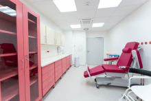 A medical room equipped with a treatment chair, cabinets and a worktop. The room is prepared to receive patients.