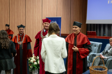 czestnicy podchodzą kolejno do przedstawicieli uczelni ubranych w ceremonialne togi akademickie.