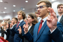Students stand with their hands raised while taking the oath.