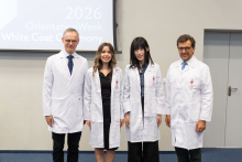 Four people pose for a group photo during the ceremony. They are all wearing white coats.