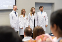 Four people wearing white coats pose for a group photo during the ceremony.