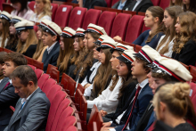 Students wearing student caps take their seats in the auditorium and attend the inauguration of the academic year.