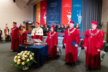 University authorities wearing ceremonial academic gowns stand on stage during the inauguration of the academic year.