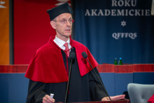 A person wearing an academic gown delivers a lecture or speech at the lectern.