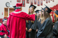 Female graduates and the Vice-Rector during the farewell. They are all wearing academic gowns and smiling.