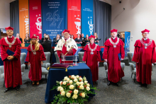 University authorities wearing red academic gowns stand in front of the stage during the inauguration of the academic year.