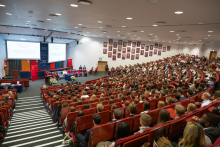 A wide view of the auditorium during the inauguration of the academic year. University authorities are seated on stage, while the audience is filled with participants attending the event.
