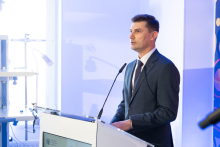 A man speaks at a lectern during an event at the Department of Cardiac, Thoracic Surgery and Transplantology. Part of the clinical room and medical equipment can be seen in the frame.