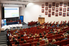 Uczestnicy Kongresu Pharmacovigilance Polska 2026 siedzą w auli Warszawskiego Uniwersytetu Medycznego. Na scenie jedna osoba prowadzi prezentację, a dwie siedzą za stołem. Na ekranie wyświetla się slajd dotyczący pharmacovigilance.