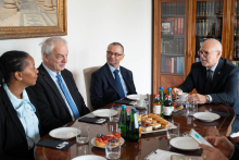 Cztery osoby siedzą przy stole podczas oficjalnego spotkania. Rozmawiają.