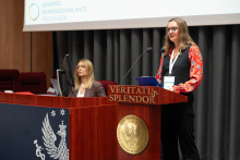 Jedna osoba przemawia przy mównicy z dwoma mikrofonami podczas Kongresu Pharmacovigilance Polska 2026. Obok stoi baner Warszawskiego Uniwersytetu Medycznego.