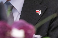 Zbliżenie na przypinkę z flagami Polski i Japonii umieszczoną na marynarce uczestnika spotkania.
