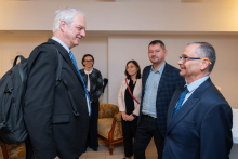 Pięć osób rozmawia podczas spotkania. Dwie osoby stoją na pierwszym planie, a trzy kolejne znajdują się za nimi.