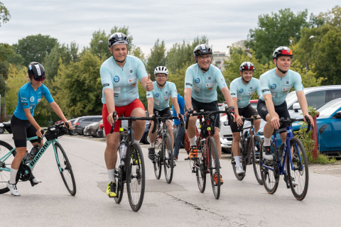 grupa osób w kaskach i sportowych strojach jedzie na rowerach