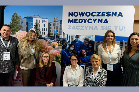 Grupa uczestników z WUM, którzy pozują do zdjęcia na tle baneru "Nowoczesna medycyna".