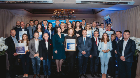 A group of elegantly dressed people pose for a group photo. Some of them are holding framed diplomas in their hands.