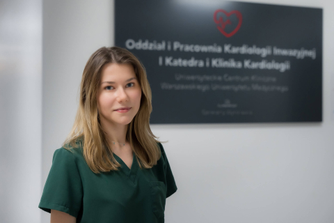 Młoda kobieta, ubrana w fartuch lekarski, pozuje do zdjęcia.