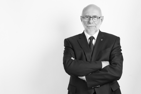 Starszy mężczyzna, ubrany elegancko, patrzy w obiektyw aparatu.