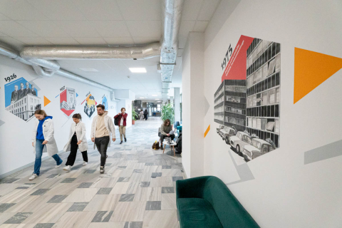 Pharmacy students in white lab coats walking down a corridor with a colorful mural.