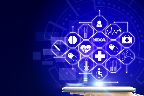 A hand holding a tablet with a creative, blue‑glowing medical interface against a dark background.