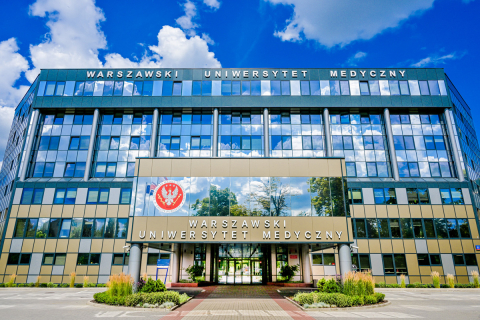 Główny budynek Warszawskiego Uniwersytetu Medycznego. Wielokondygnacyjny gmach z przeszkloną elewacją i wejściem pośrodku. Nad wejściem widoczny jest herb uczelni oraz napis „Warszawski Uniwersytet Medyczny”. Na dachu znajduje się duży napis z pełną nazwą uczelni. Przed budynkiem biegnie utwardzona alejka otoczona zielenią.