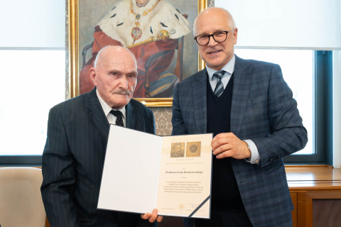 Dwie osoby pozują do pamiątkowego zdjęcia, prezentując otwarty dyplom związany z Medalem im. dr. Tytusa Chałubińskiego.