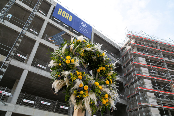 Wieniec z kwiatów zawieszany na konstrukcji budynku Centrum Symulacji Medycznych